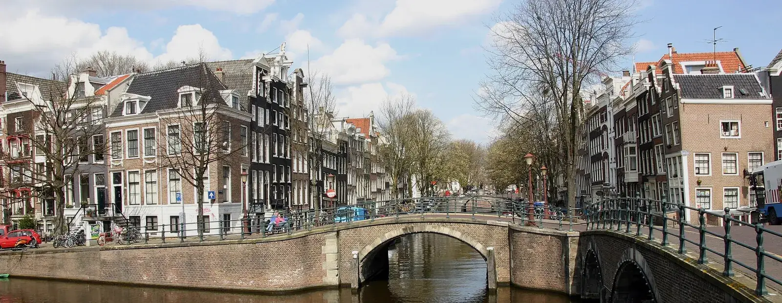 A canal in Amsterdam with a brick arch bridge, canal houses and bicycles along the quay.